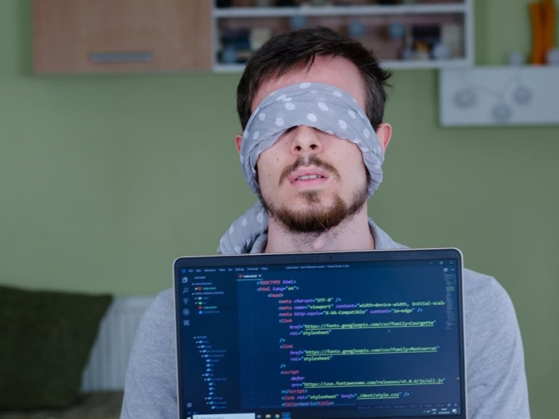 dude blindfolded behind a monitor with code on it